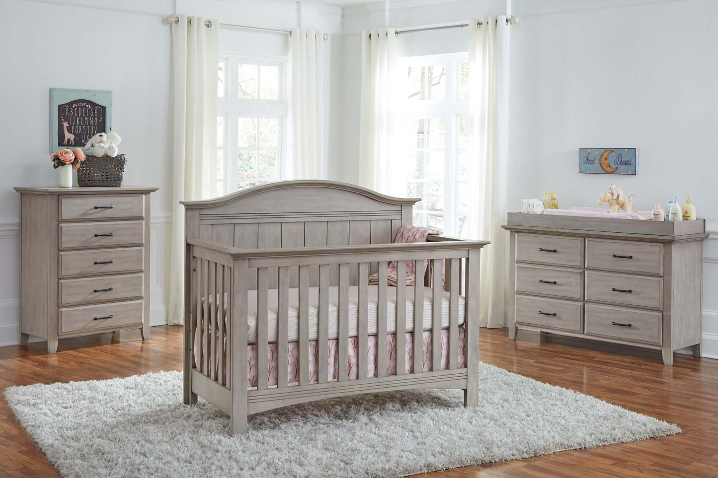 Chandler Changing Topper - Lifestyle Image Inclined Side View of Chandler Changing Topper Stone Wash on Top of 6 Drawer Dresser Beside Crib