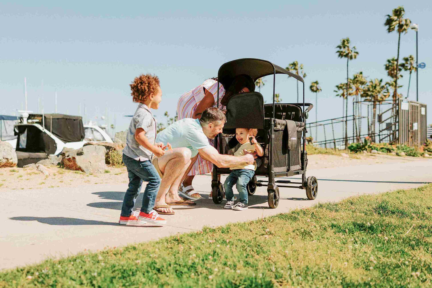 W4 Elite Quad Stroller Wagon - Lifestyle Image of Father helping Toddler to get out of W4 Elite Quad Stroller Wagon Black