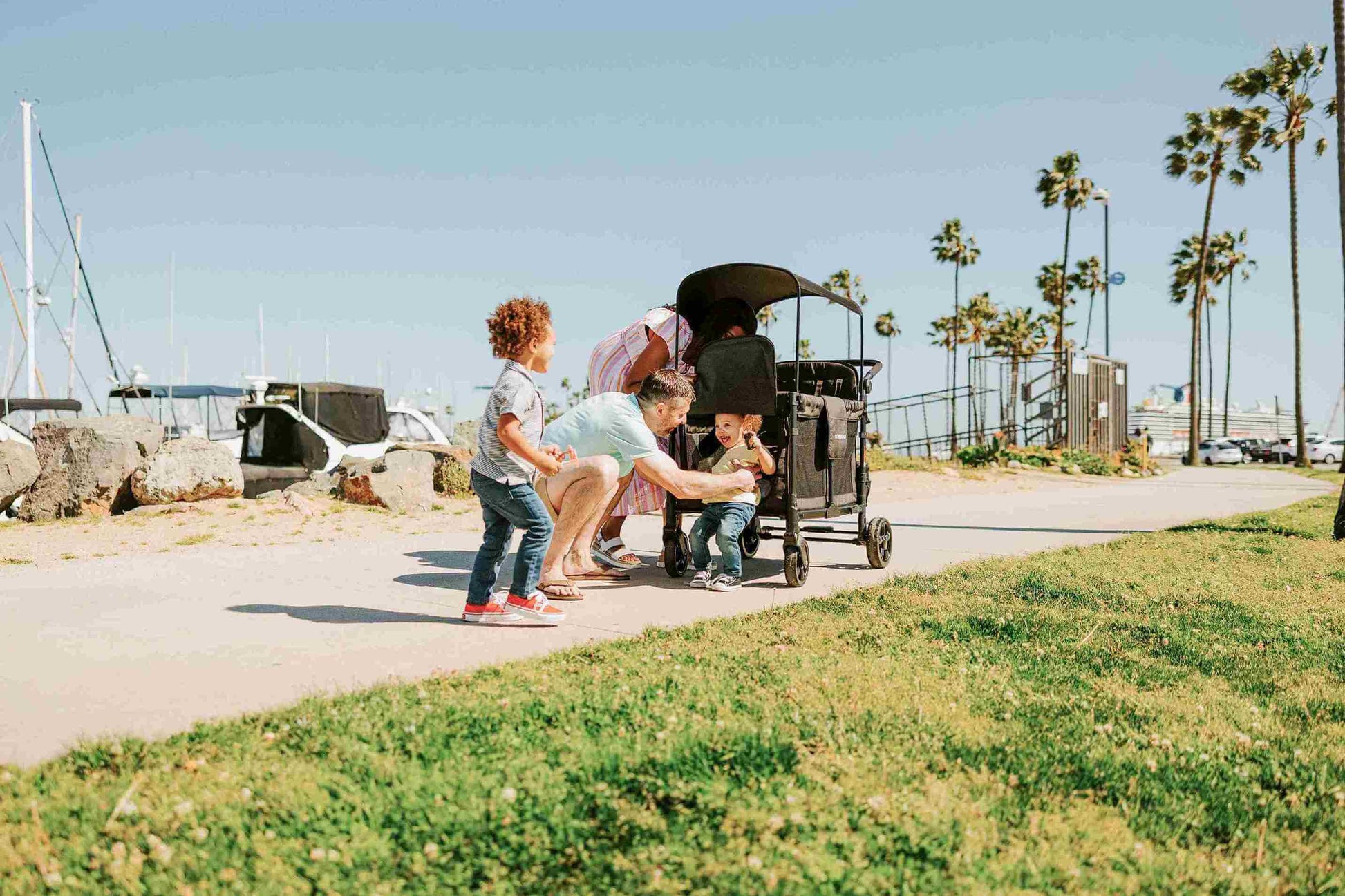 W4 Elite Quad Stroller Wagon - Lifestyle Image of Father helping Toddler to get out of W4 Elite Quad Stroller Wagon Black Camo