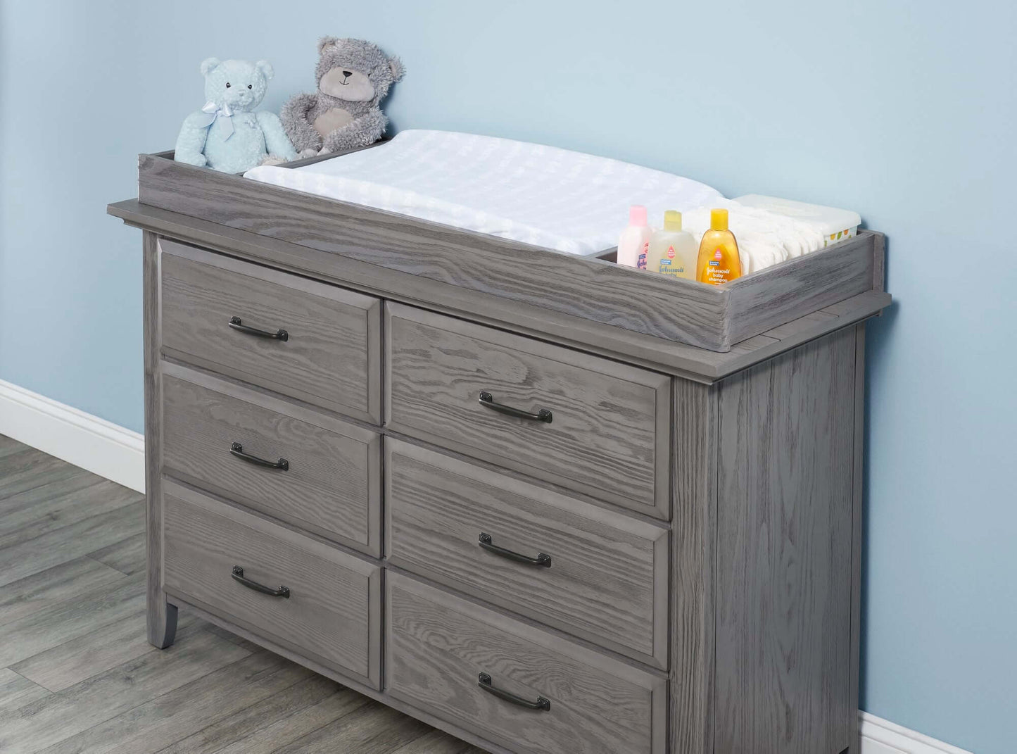 Chandler Changing Topper - Lifestyle Image Inclined Side View of Chandler Changing Topper Gray on Top of 6 Drawer Dresser