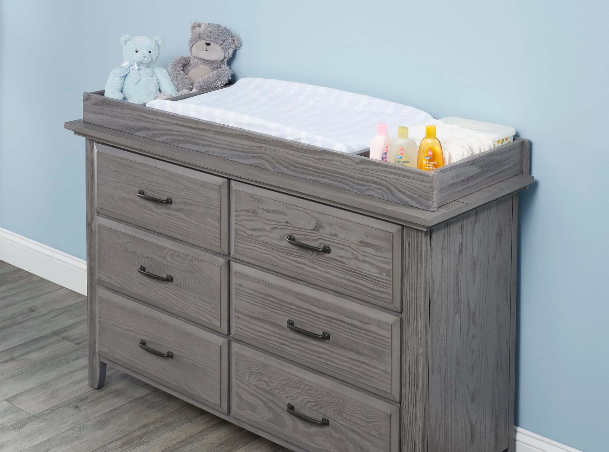 Chandler Changing Topper - Lifestyle Image Inclined Side View of Chandler Changing Topper Gray on Top of 6 Drawer Dresser