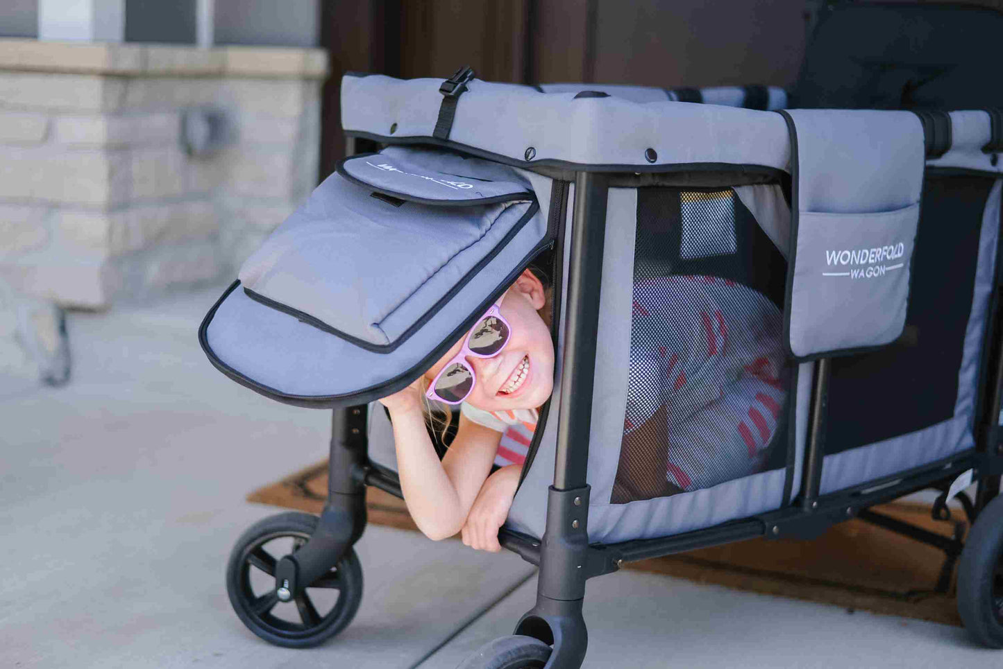 W2 Original + Double Stroller Wagon - Lifestyle Image of Baby peaking Through W2 Original + Double Stroller Wagon Gray