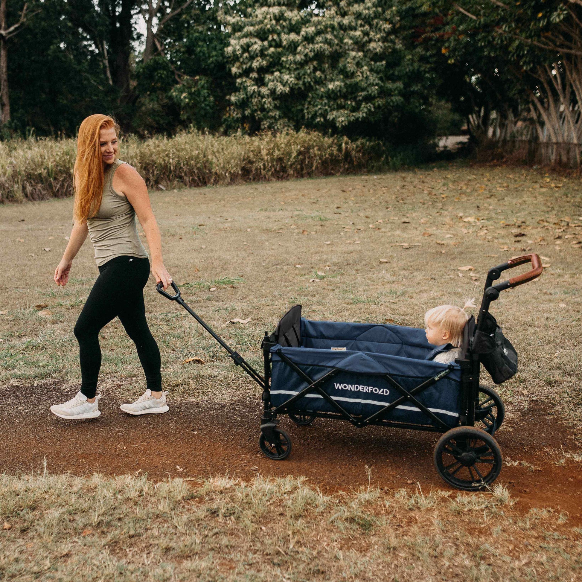 X2 Double Stroller Wagon - Lifestyle Image of Mother Holding Pull Handle of X2 Double Stroller Wagon with Baby Inside Wagon Navy