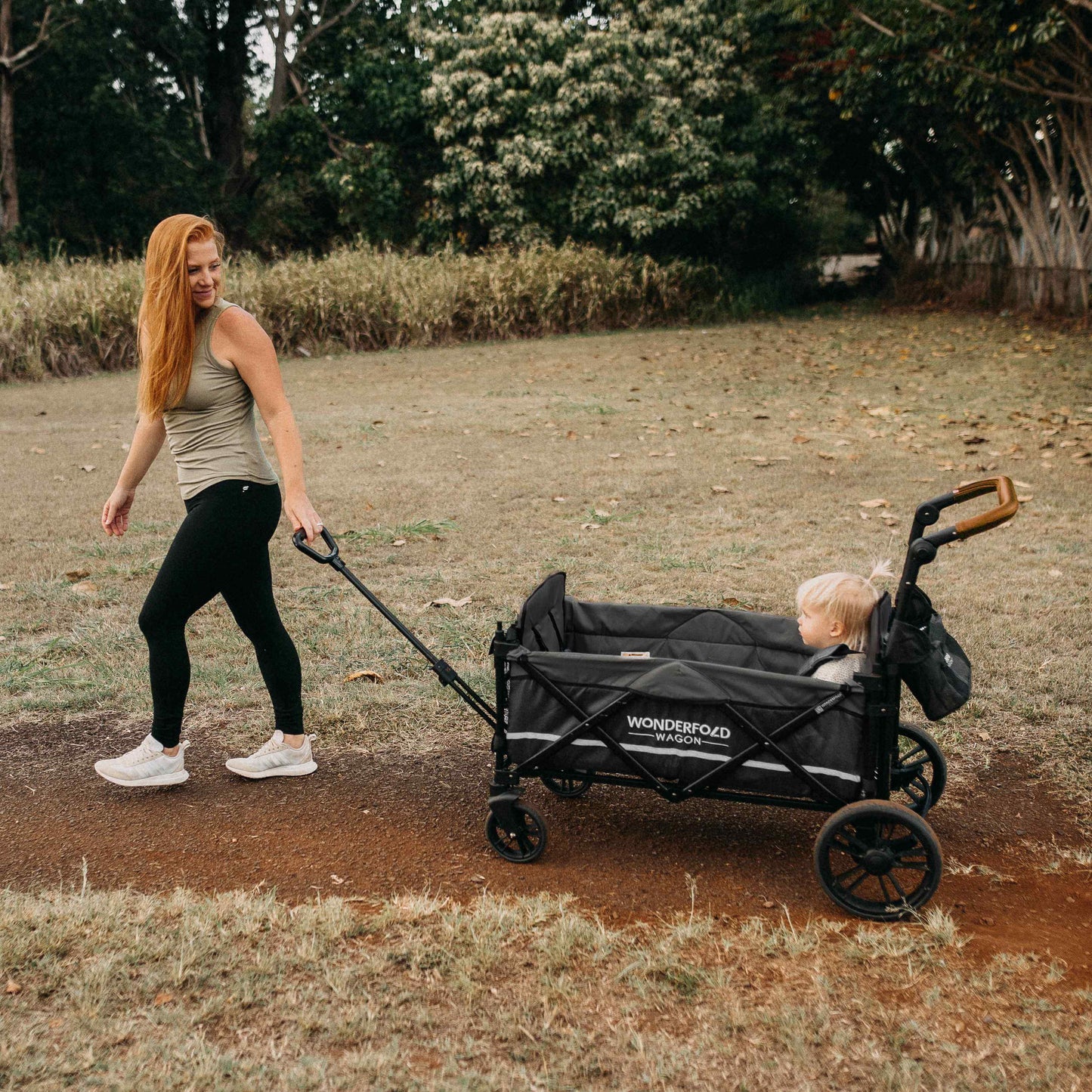 X2 Double Stroller Wagon - Lifestyle Image of Mother Holding Pull Handle of X2 Double Stroller Wagon with Baby Inside Wagon Black