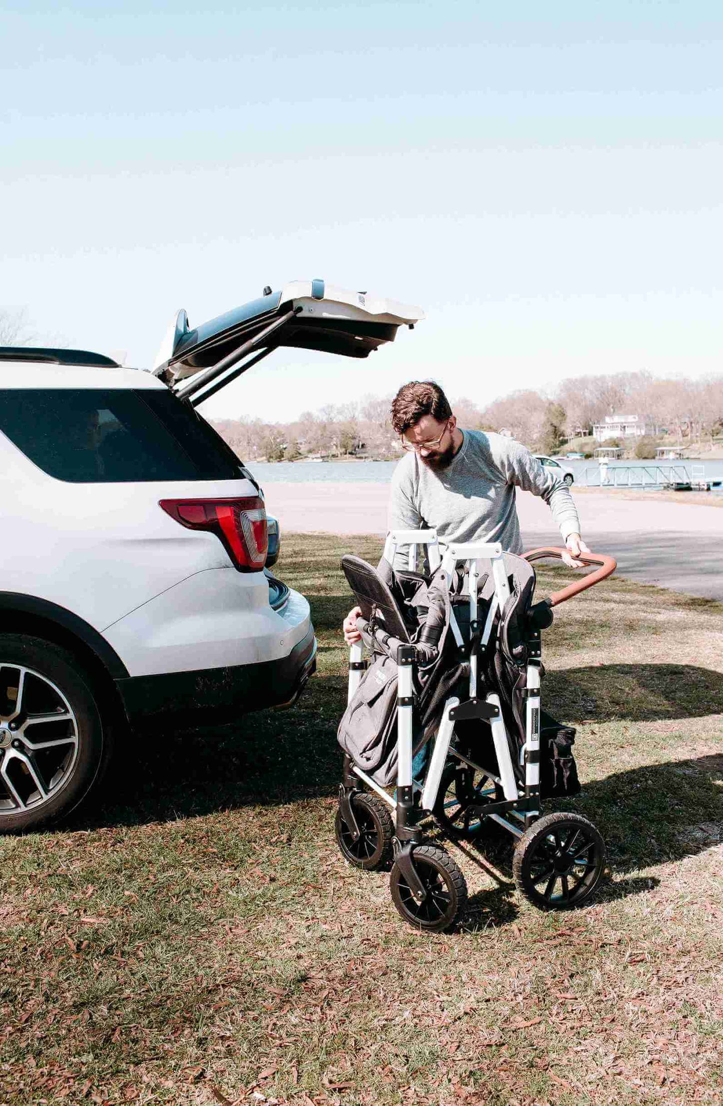 W4 Luxe Quad Stroller Wagon - Lifestyle Image of Man Unfolding W4 Luxe Quad Stroller Wagon Gray
