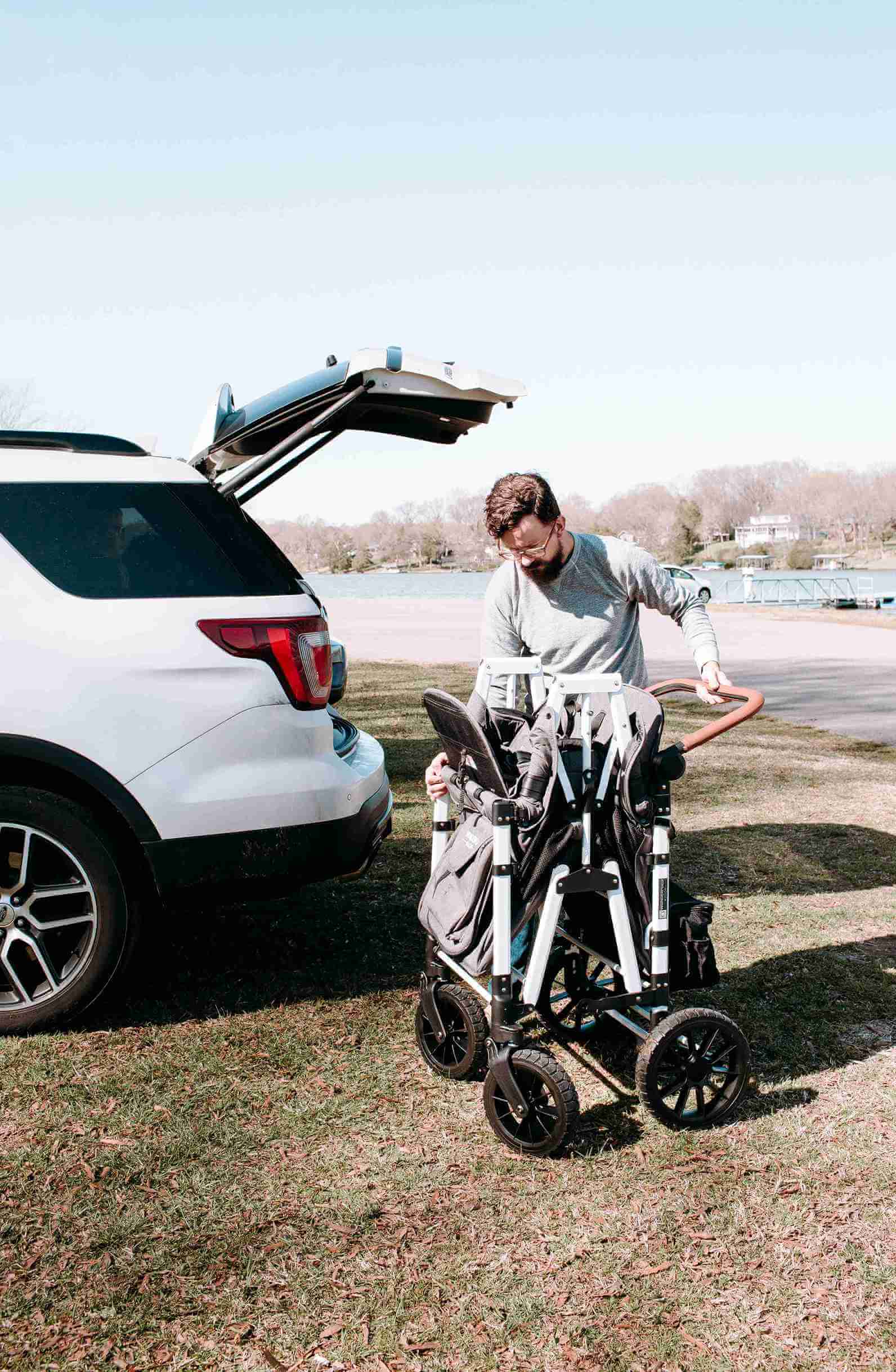 W4 Luxe Quad Stroller Wagon - Lifestyle Image of Man Unfolding W4 Luxe Quad Stroller Wagon Gray