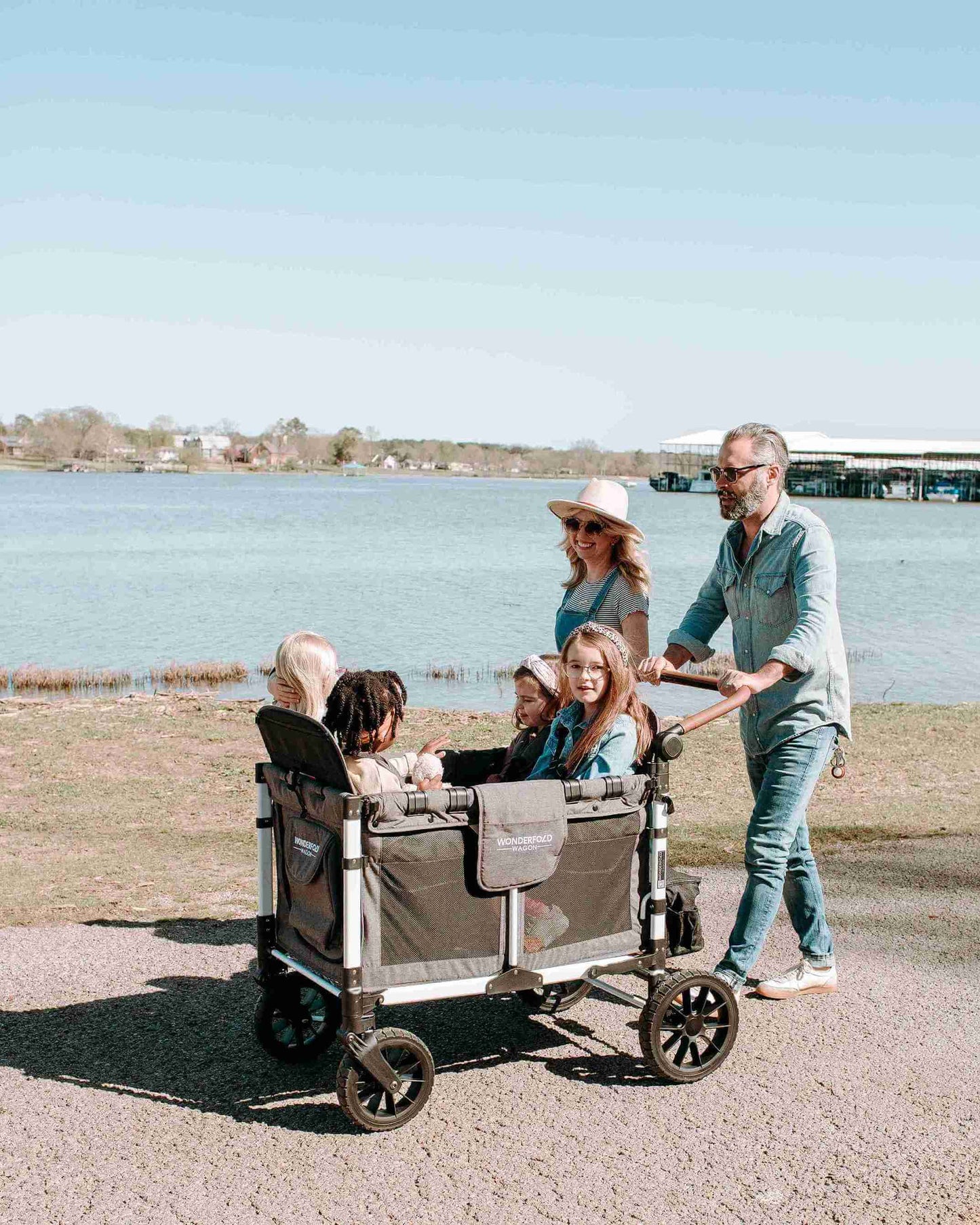 W4 Luxe Quad Stroller Wagon - Lifestyle Image of Full Family on Vacation with W4 Luxe Quad Stroller Wagon Gray