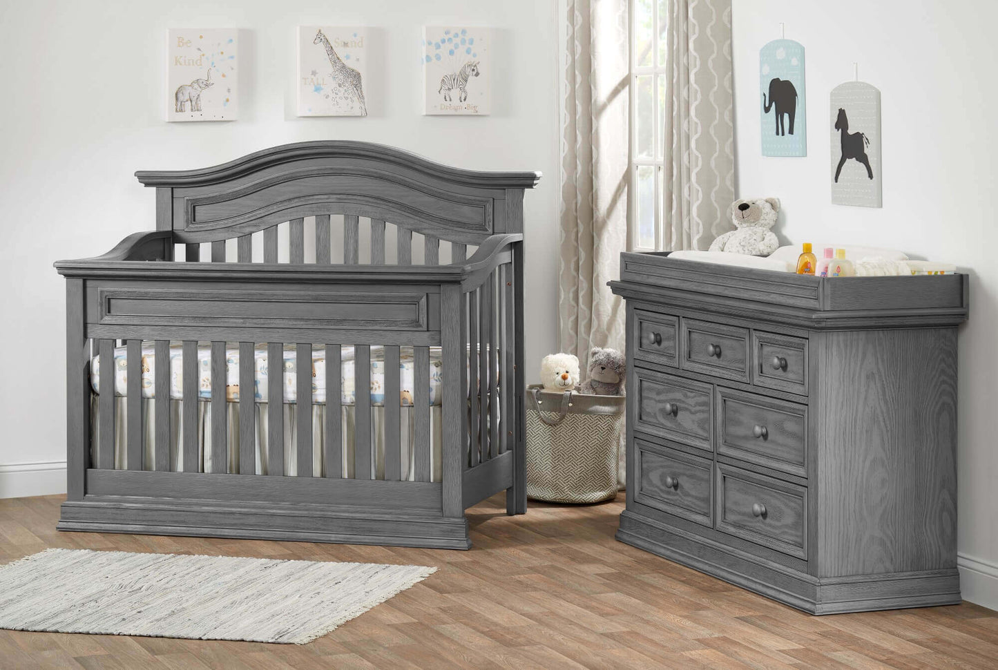 Glenbrook Changing Topper - Lifestyle Image Inclined Side View of Glenbrook Changing Topper Gray on Top of Double Drawer Dresser Beside Crib