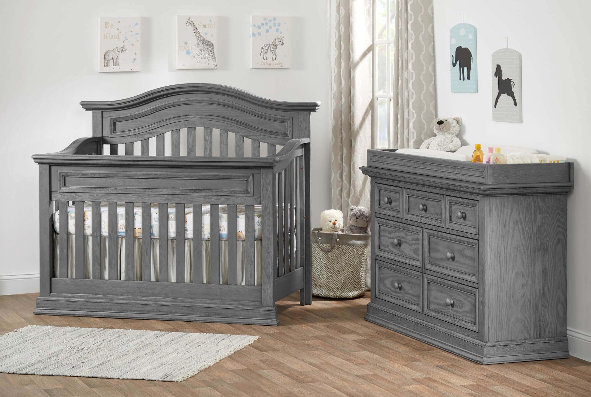 Glenbrook Changing Topper - Lifestyle Image Inclined Side View of Glenbrook Changing Topper Gray on Top of Double Drawer Dresser Beside Crib