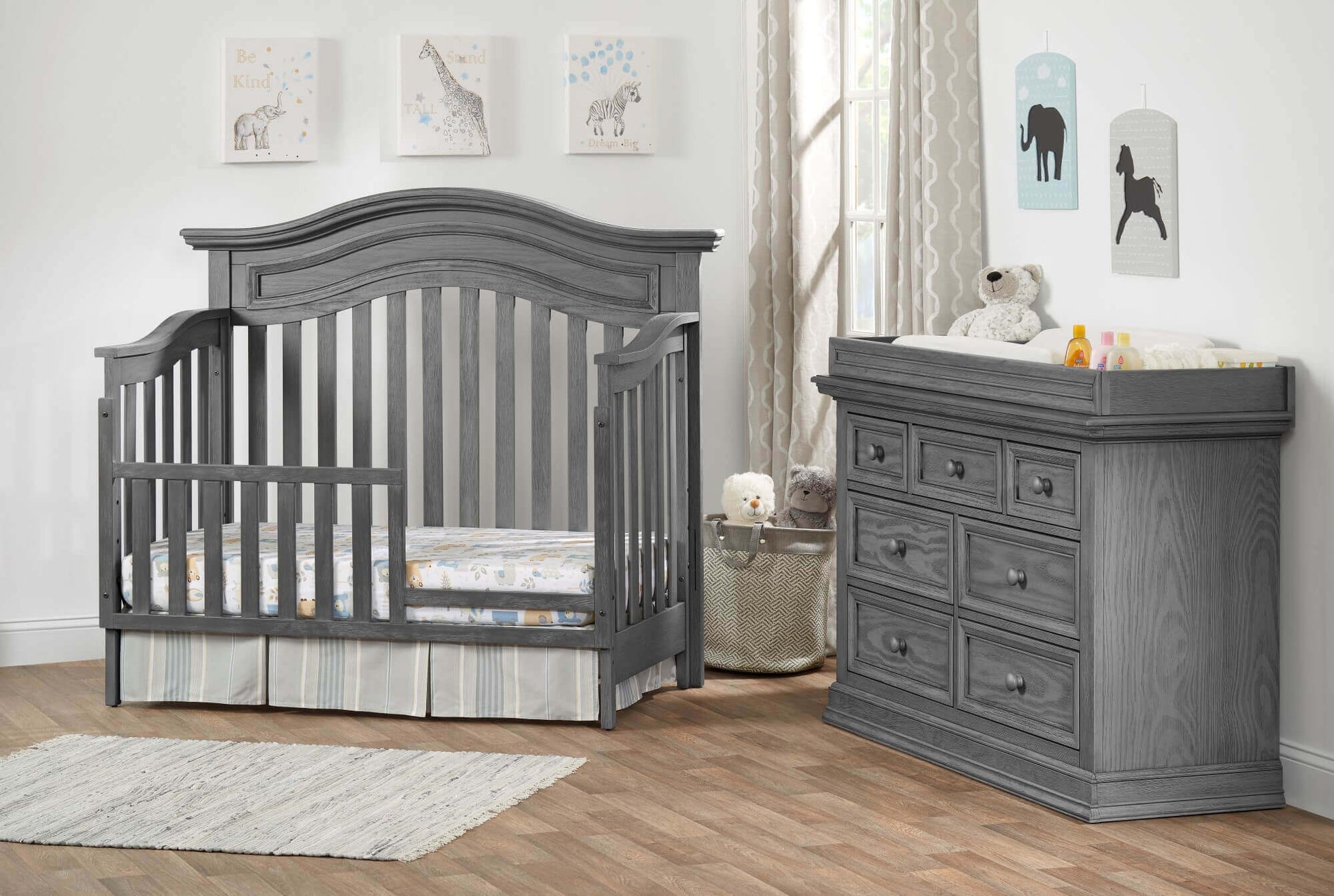 Glenbrook 4-in-1 Convertible Crib - Lifestyle Image Inclined Side View of Glenbrook 4-in-1 Convertible Crib Graphite Gray with Guard Rail and 7 Drawer Dresser