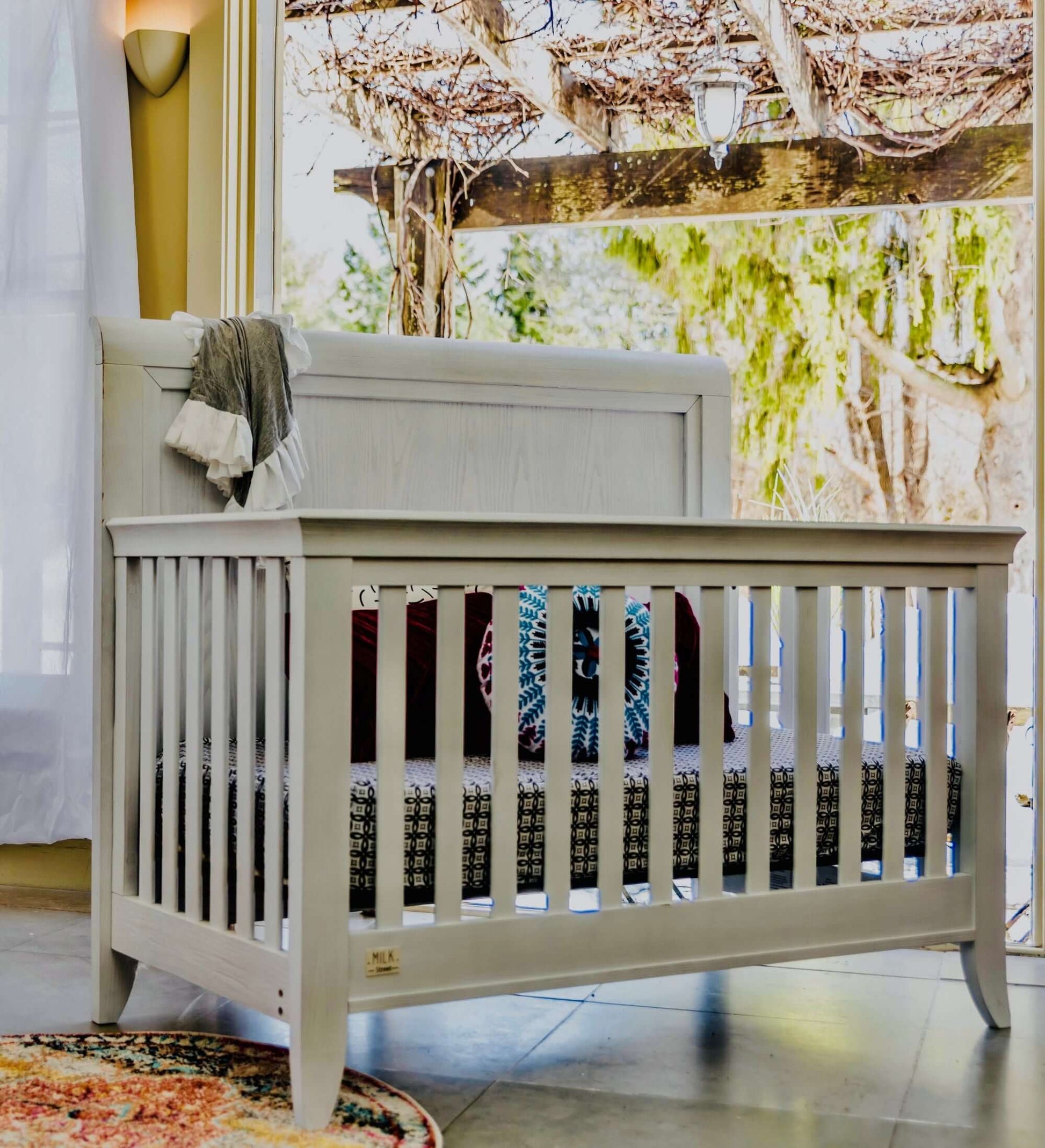 Cameo Sleigh 4-in-1 Convertible Crib - Lifestyle Image Side View of Sleigh 4-in-1 Convertible Crib Steam-1