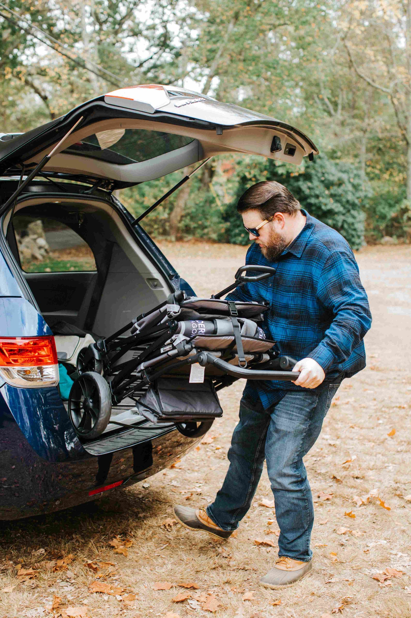 X2 Double Stroller Wagon - Lifestyle Image of Man Withdrawing X2 Double Stroller Wagon Gray From Car Trunk
