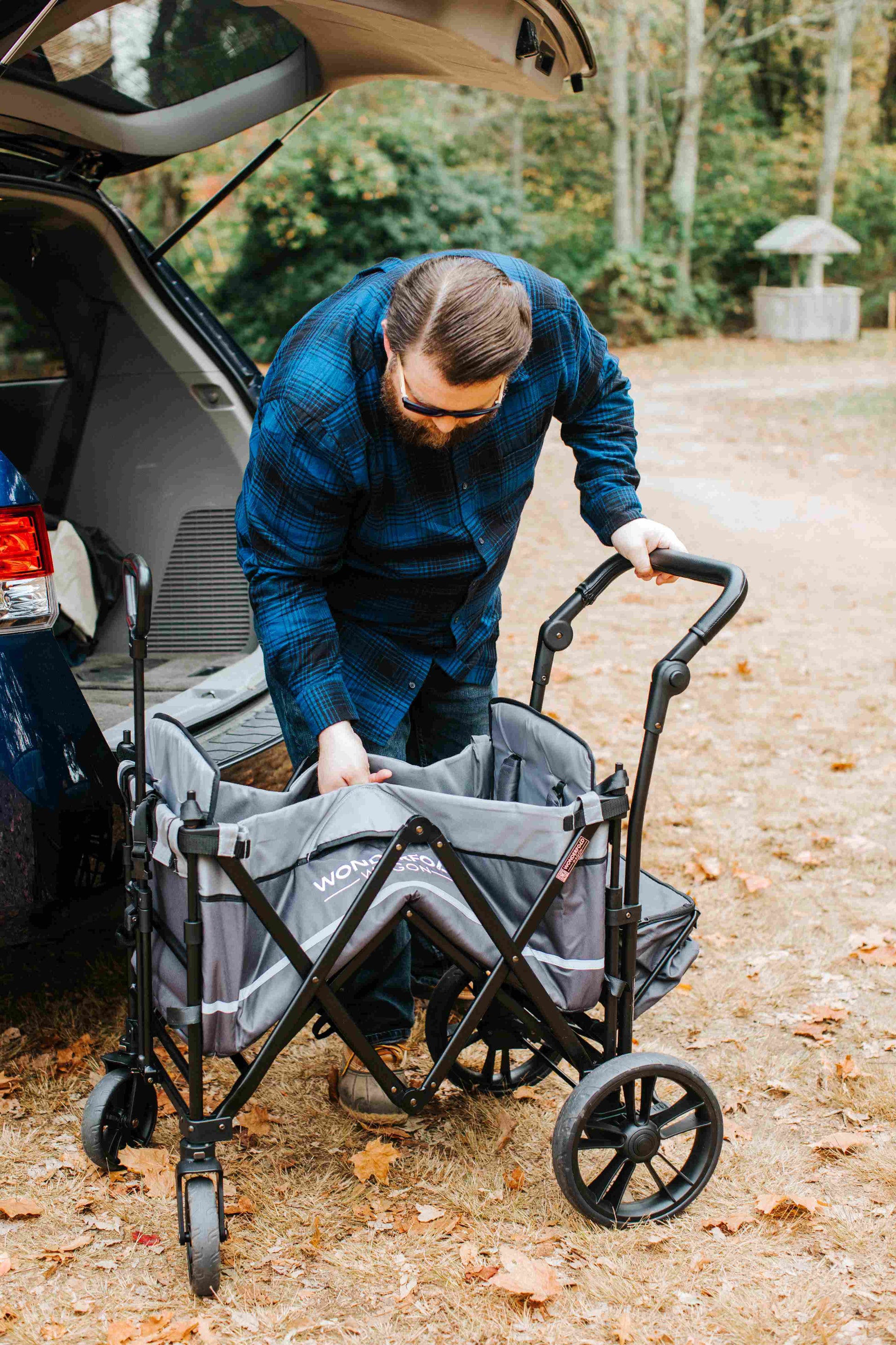 X2 Double Stroller Wagon - Lifestyle Image of Man Unfolding X2 Double Stroller Wagon Gray