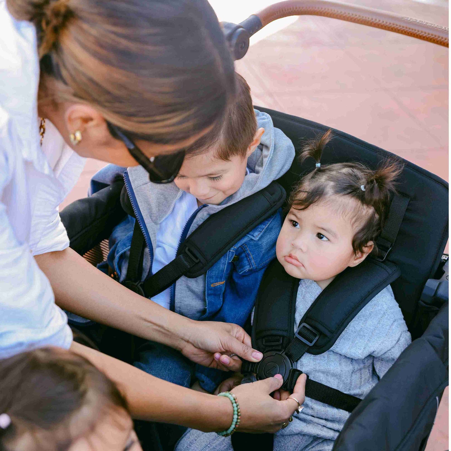 L4 Quad Stroller Wagon - Lifestyle Image of Mother Locking the Harness of The L4 Quad Stroller Wagon Gray
