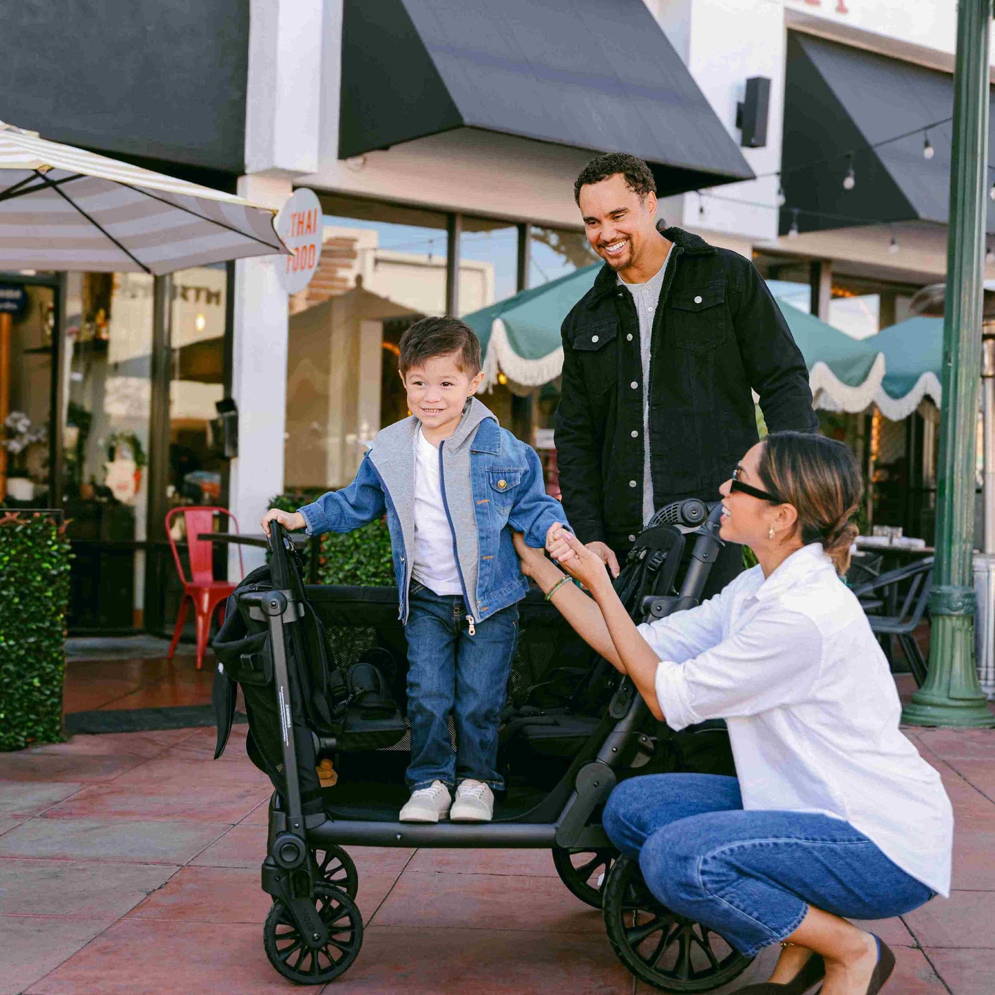 L4 Quad Stroller Wagon - Lifestyle Image Side View of the L4 Quad Stroller Wagon Black Child Hopping -1