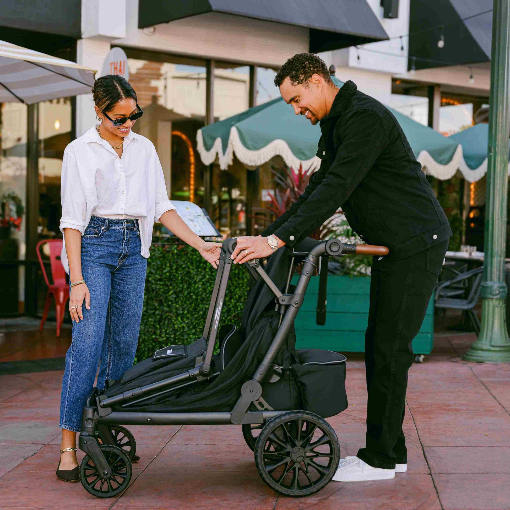 L4 Quad Stroller Wagon - Lifestyle Image of Women Helping Man Fold The L4 Quad Stroller Wagon Gray