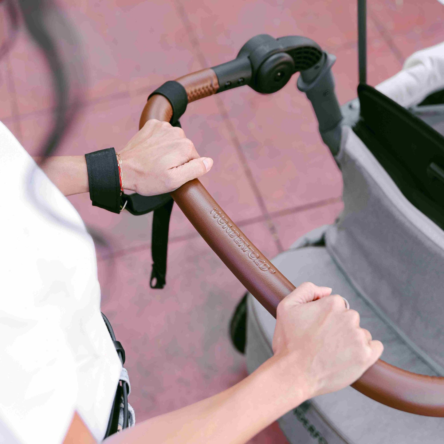 L4 Quad Stroller Wagon - Lifestyle Image Holding Handle of L4 Quad Stroller Wagon Gray