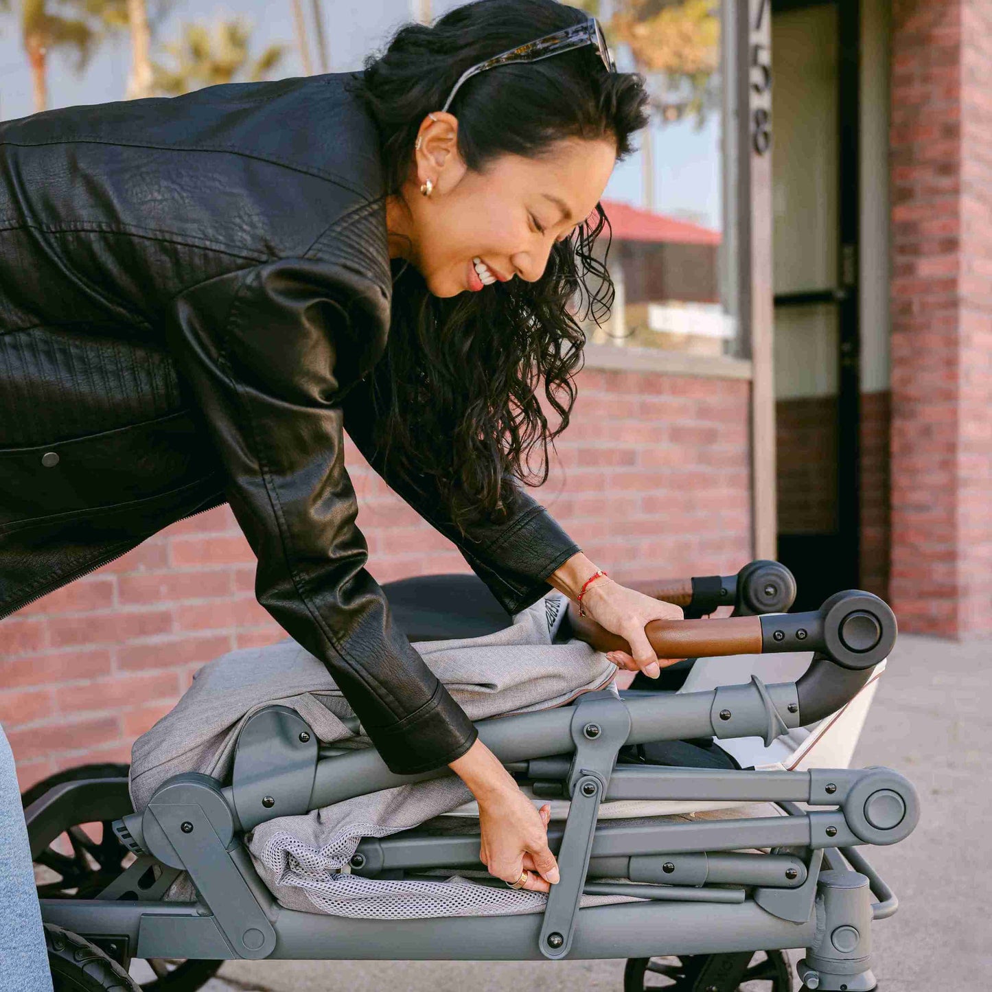 L4 Quad Stroller Wagon - Lifestyle Image Mother Folding The L4 Quad Stroller Wagon Gray