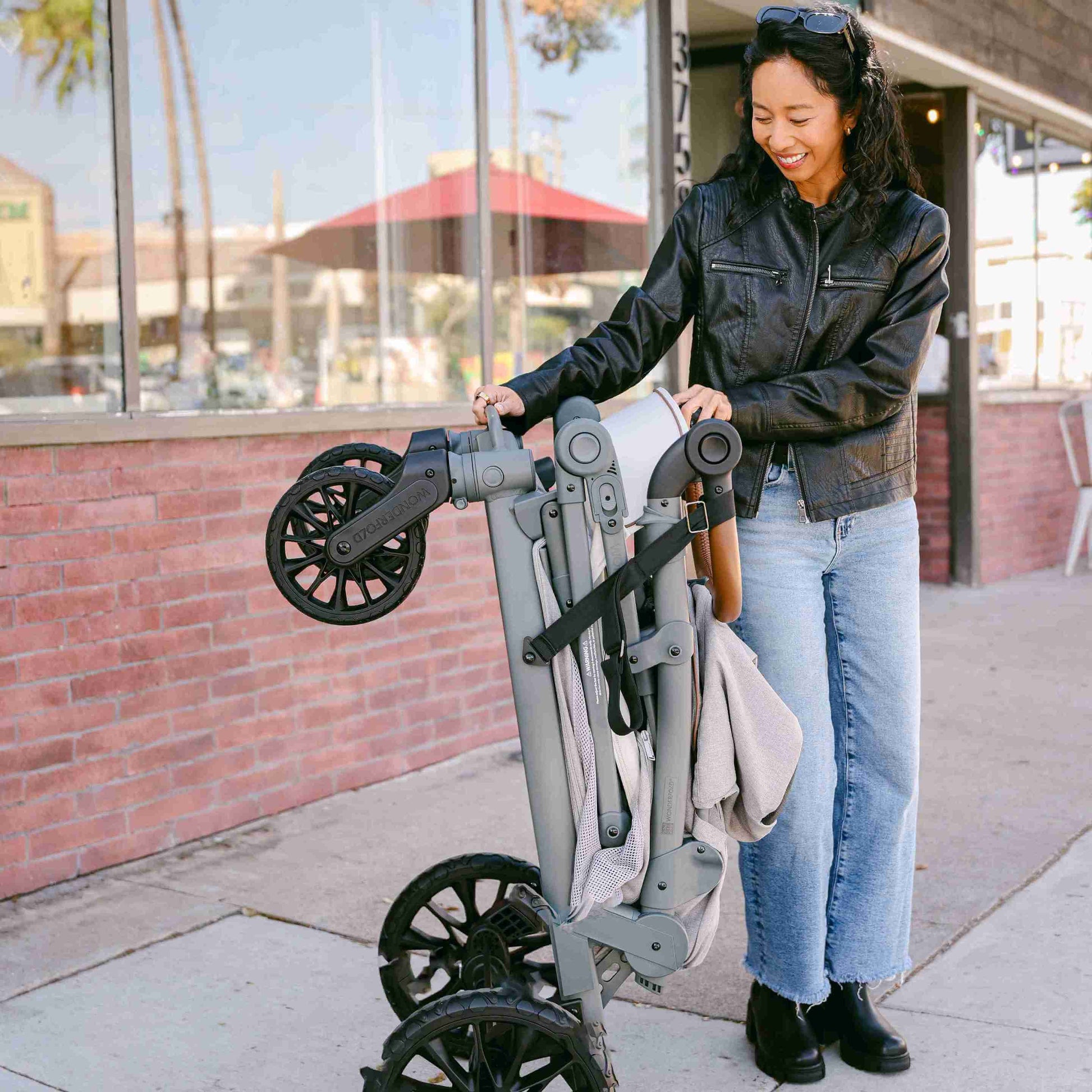 L4 Quad Stroller Wagon - Lifestyle Image Mother Folding The L4 Quad Stroller Wagon Gray