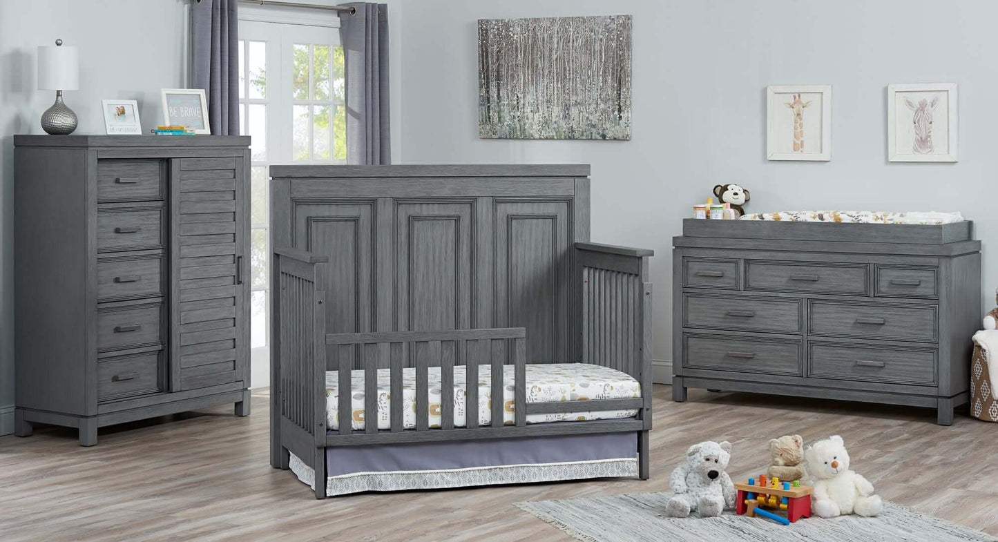 Manchester 4 In 1 Convertible Crib - Lifestyle Image Inclined Side View of Manchester 4 In 1 Convertible Crib Rustic Gray with Guard Rail