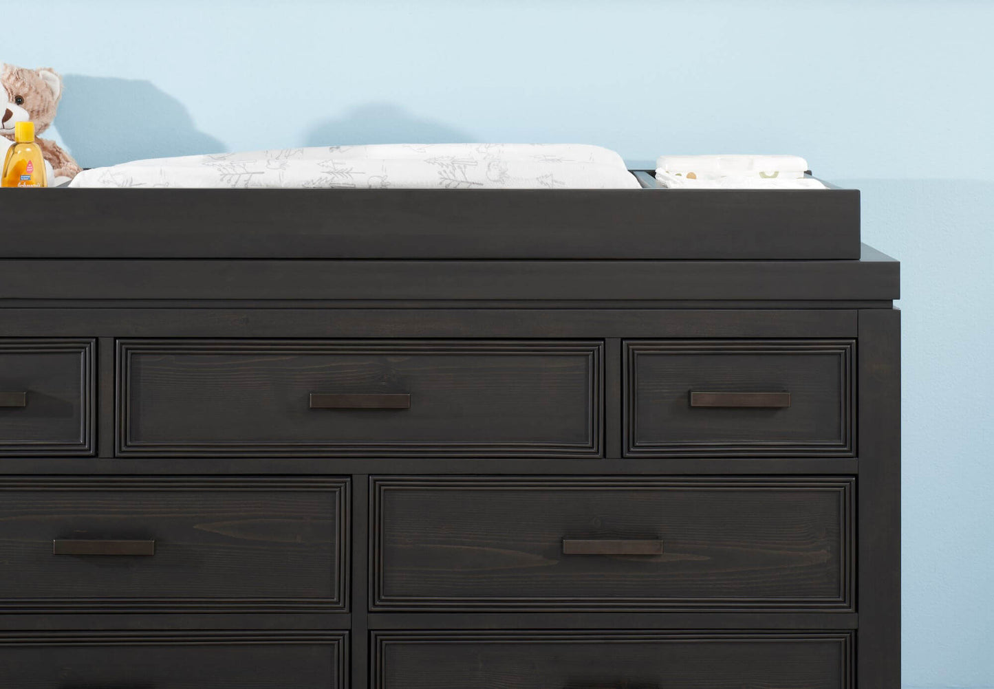 Manchester Changing Topper - Lifestyle Image Front View of Manchester Changing Topper Black Iron on Top of 6 Drawer Dresser