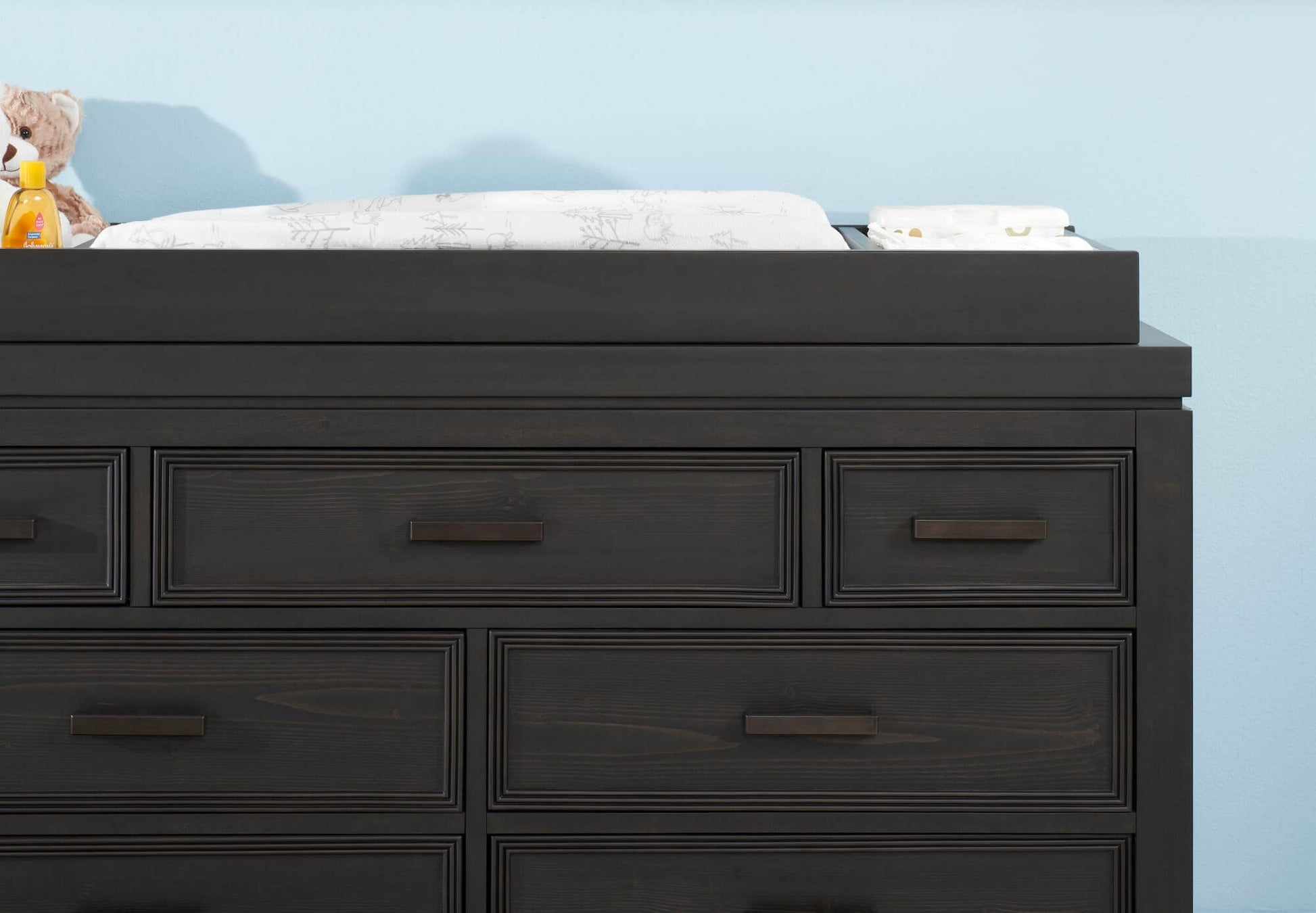 Manchester Changing Topper - Lifestyle Image Front View of Manchester Changing Topper Black Iron on Top of 6 Drawer Dresser