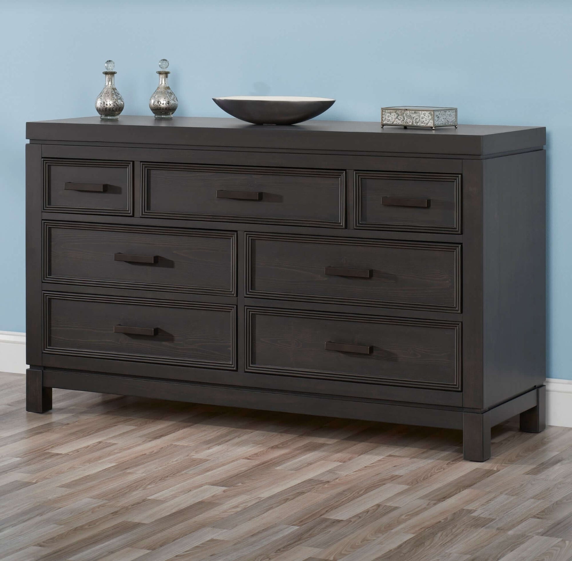 Manchester Changing Topper - Lifestyle Image Inclined Side View of Manchester Changing Topper Black Iron on Top of 6 Drawer Dresser
