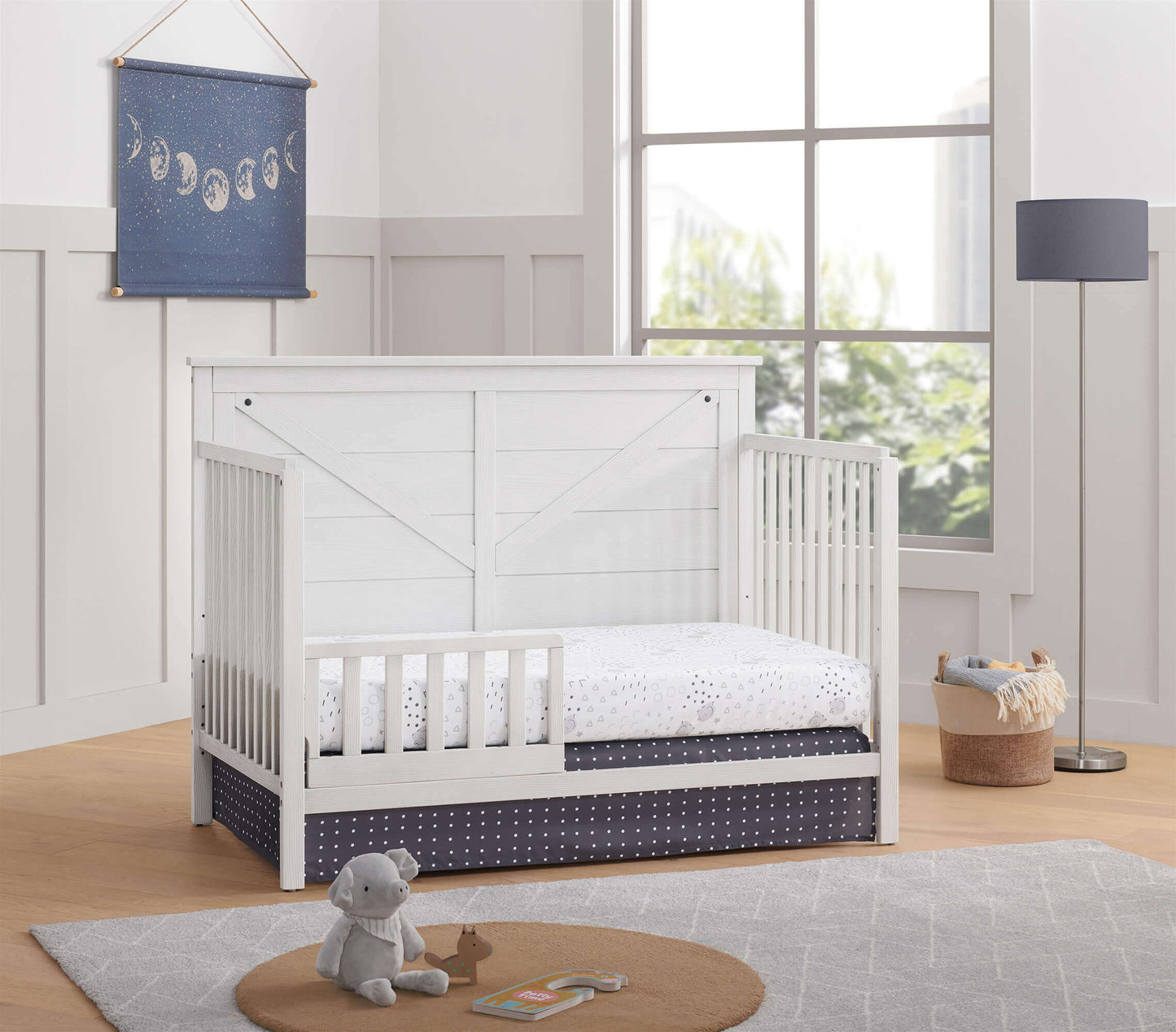 Montauk 4-in-1 Convertible Crib - Lifestyle Image Inclined Side View of Montauk 4-in-1 Convertible Crib Barn White with Guard Rail