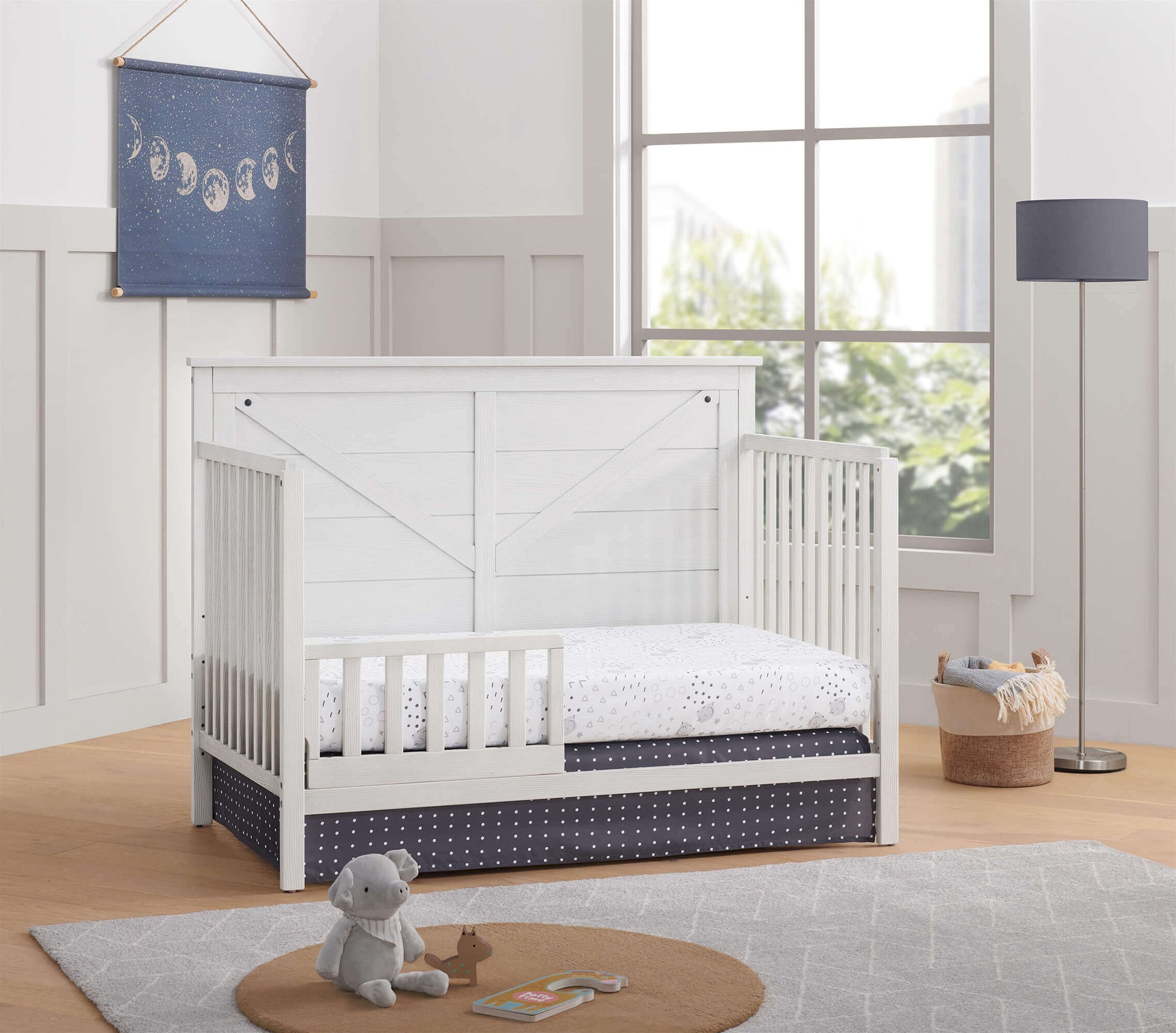 Montauk 4-in-1 Convertible Crib - Lifestyle Image Inclined Side View of Montauk 4-in-1 Convertible Crib Barn White with Guard Rail