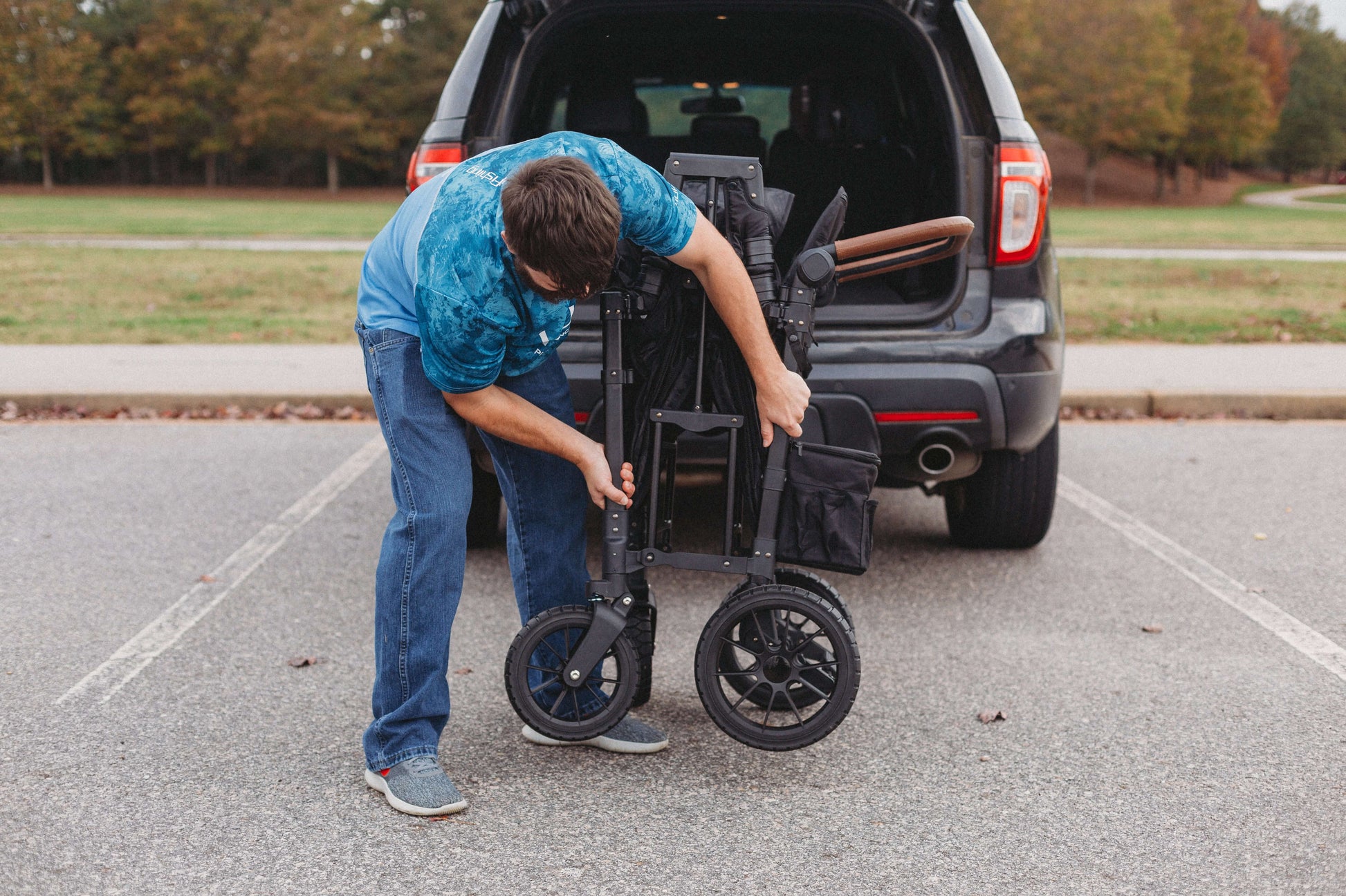 W2 Luxe Double Stroller Wagon - Lifestyle Image of Man Folded W2 Luxe Double Stroller Wagon Black