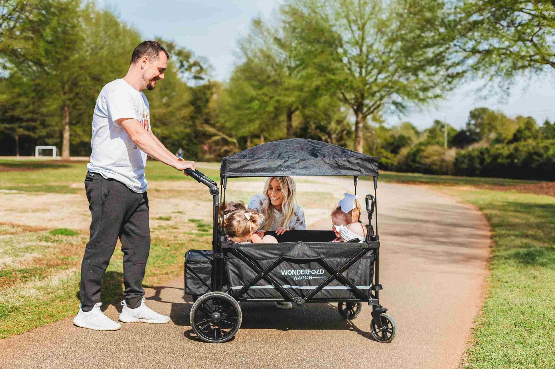 X4 Push + Pull Quad Stroller Wagon - Lifestyle Image of Family Enjoying Time Together with X4 Push + Pull Quad Stroller Wagon Black on their Side
