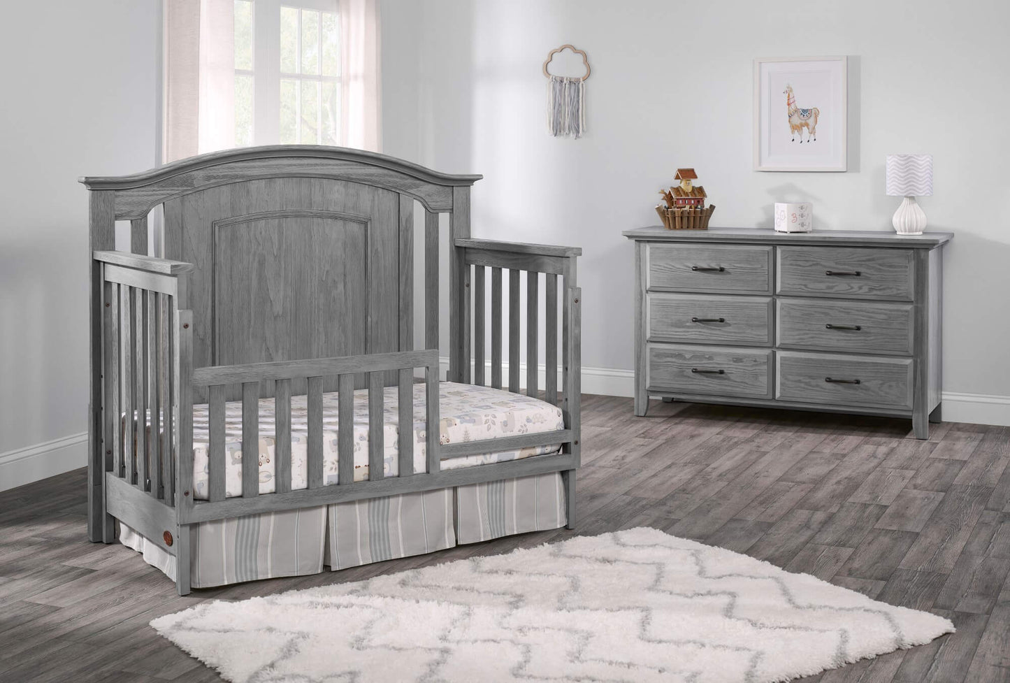 Willowbrook 4-in-1 Convertible Crib - Lifestyle Image Inclined Side View of Willowbrook 4-in-1 Convertible Crib Graphite Gray with Guard Rail