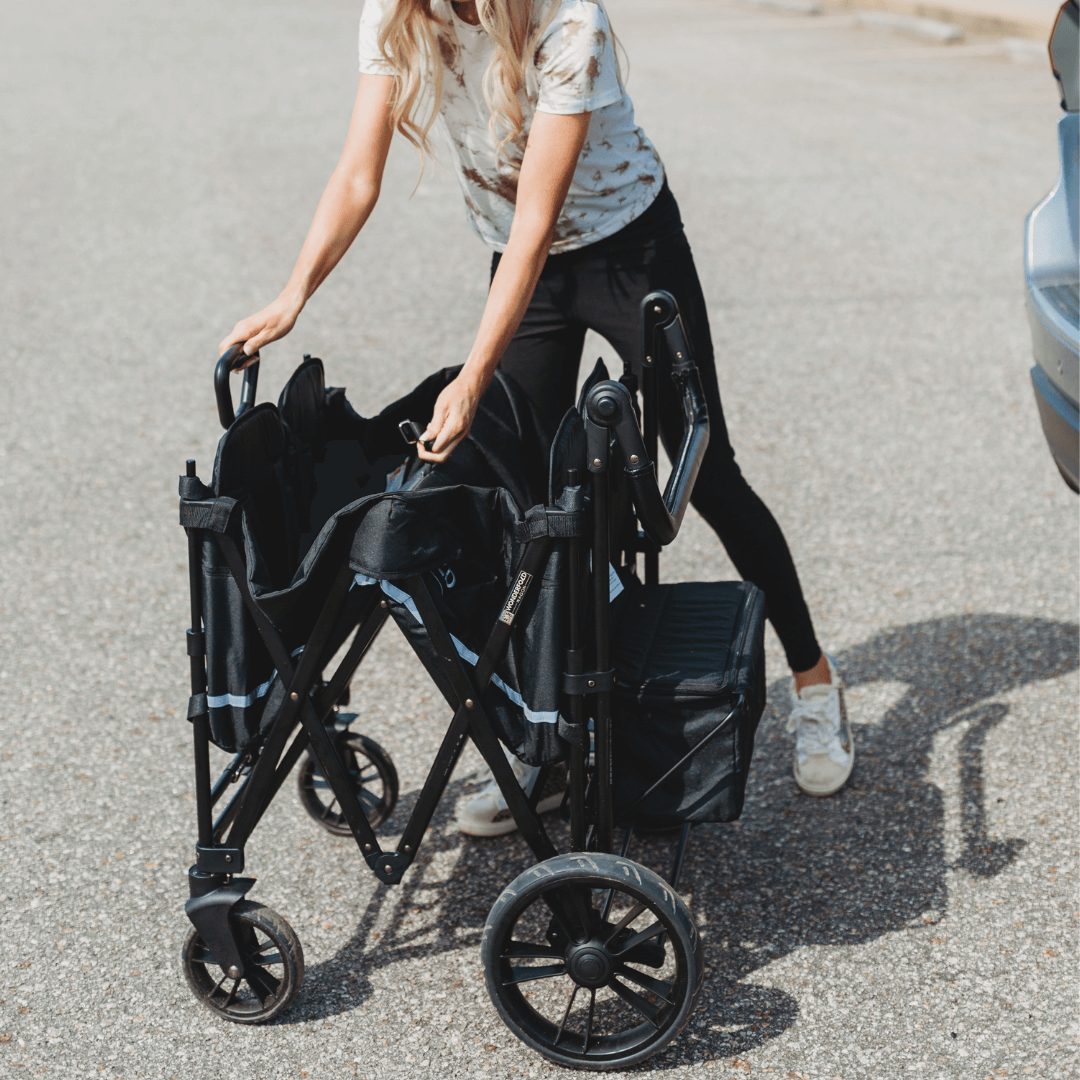 X4 Push + Pull Quad Stroller Wagon - Lifestyle Image of woman Unfolding X4 Push + Pull Quad Stroller Wagon Black