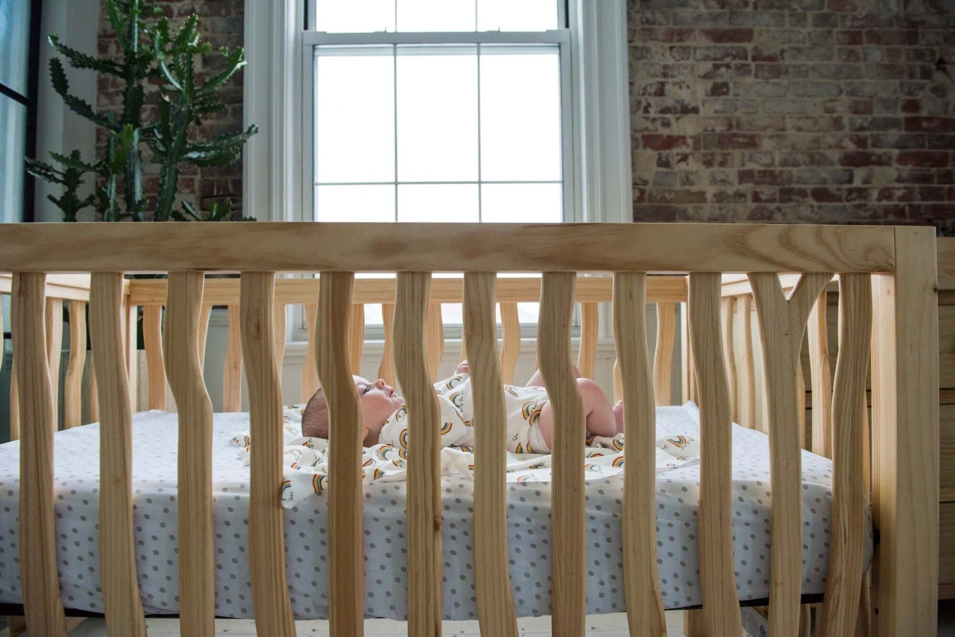 Branch 4 in 1 Convertible Crib - Zoomed Side View Lifestyle Image of 4 in 1 Convertible Crib Acacia with Baby Inside